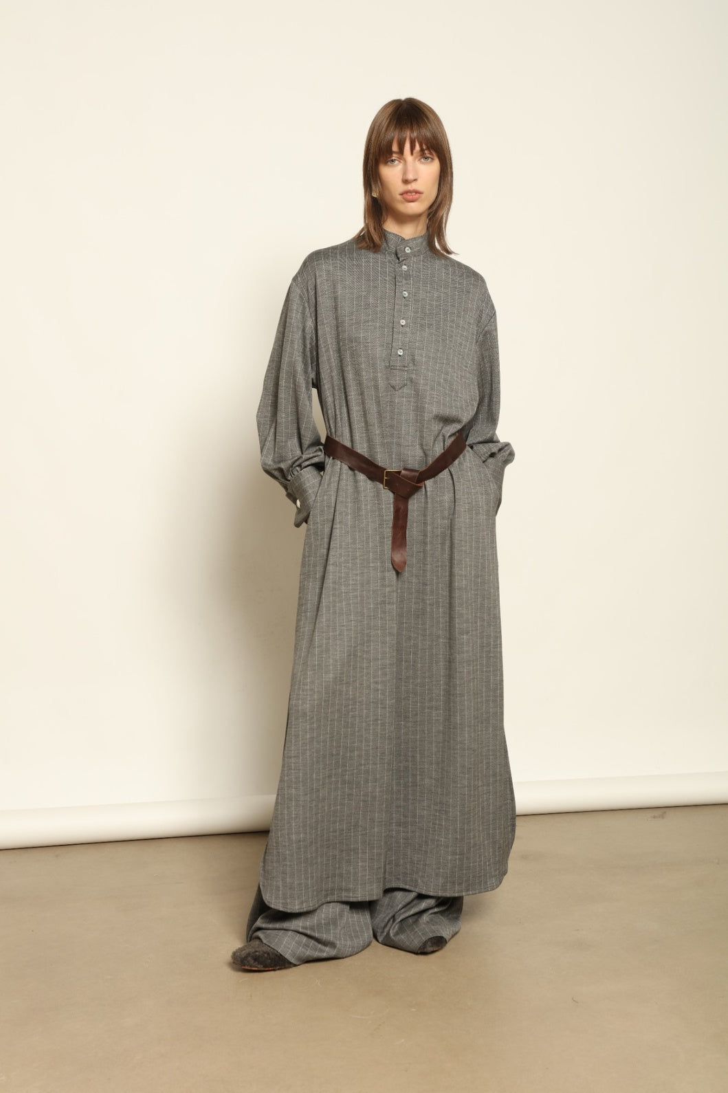 Model is wearing the Paul Dress by House of Nomad Stories, made from sustainable wool with vertical stripes, a stand collar, and versatile styling for effortless elegance.