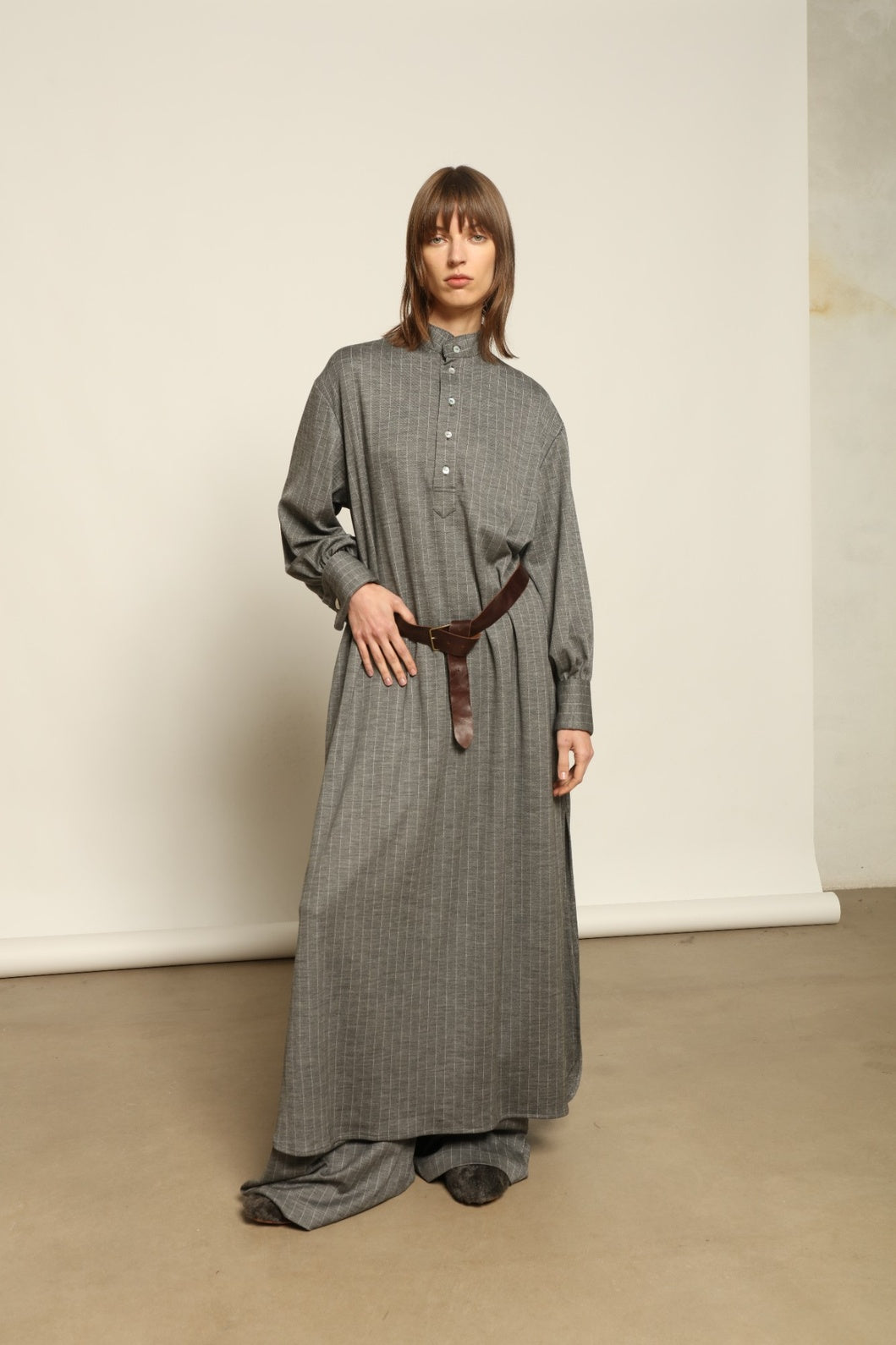 Model is wearing the Paul Dress by House of Nomad Stories, made from sustainable wool with vertical stripes, a stand collar, and versatile styling for effortless elegance.