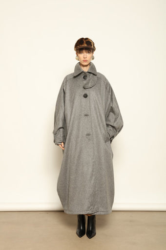 Model is wearing the Ryadh Long Coat in flannel grey by House of Woven Stories, made from merino wool and cashmere with silk lining and vintage 1960s buttons.