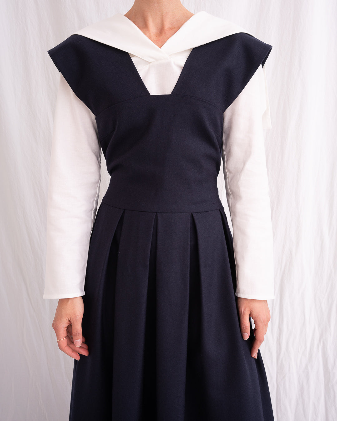 Model is wearing the Sarafan Pure New Wool Dress by Les Vacances d’Irina, a handmade navy merino wool dress with A-line silhouette, tie-back detail, horn buttons, and side pockets, available at House of Nomad Stories.