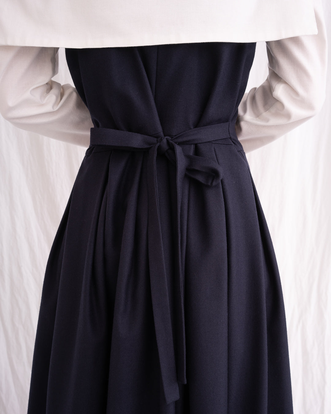 Model is wearing the Sarafan Pure New Wool Dress by Les Vacances d’Irina, a handmade navy merino wool dress with A-line silhouette, tie-back detail, horn buttons, and side pockets, available at House of Nomad Stories.