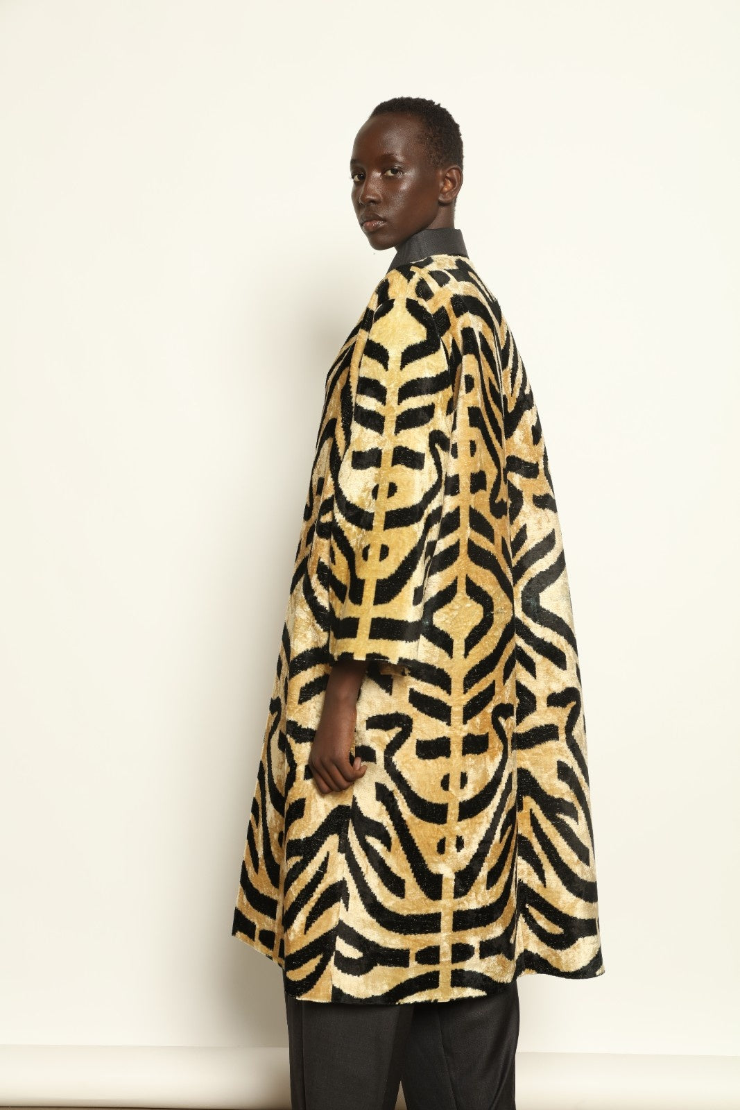 Model is wearing the Serai Ikat Velvet Coat by Aleksandra Viktor, part of House of Nomad Stories collection, handwoven Uzbek ikat velvet coat with bold geometric pattern and cobalt lining