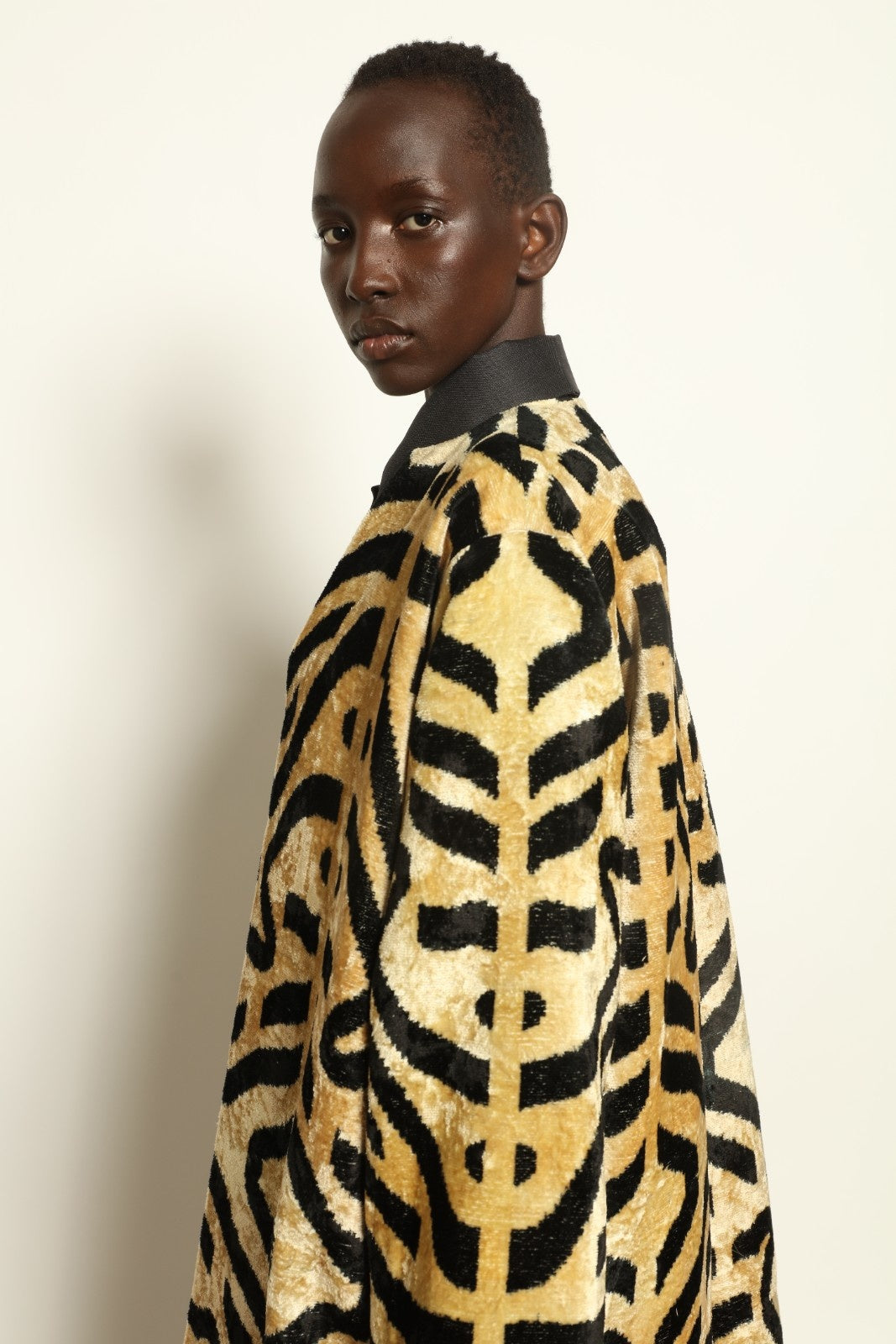 Model is wearing the Serai Ikat Velvet Coat by Aleksandra Viktor, part of House of Nomad Stories collection, handwoven Uzbek ikat velvet coat with bold geometric pattern and cobalt lining