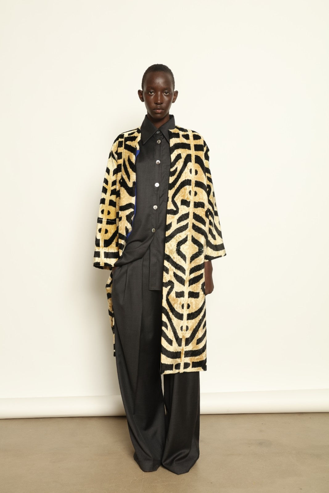 Model is wearing the Serai Ikat Velvet Coat by Aleksandra Viktor, part of House of Nomad Stories collection, handwoven Uzbek ikat velvet coat with bold geometric pattern and cobalt lining