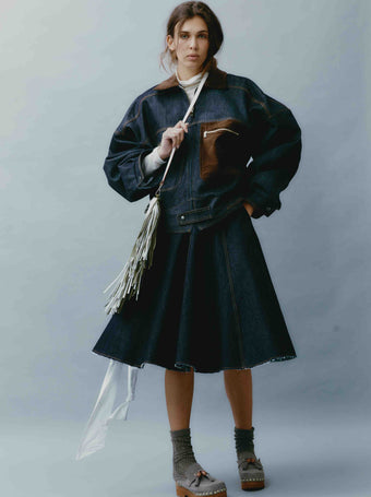 Model is wearing the Sissi Short Blue Jeans Skirt by Maison Jejia, part of the House of Nomad Stories selection, featuring dark blue denim, a structured fit, subtle edgy details, and a polished silhouette.