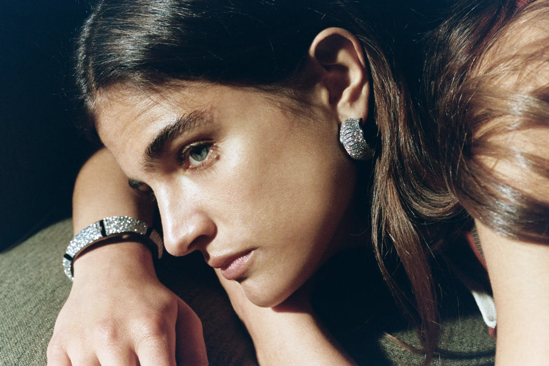 Model is wearing Tetra Crystal Silver leather bracelet by SO-LE STUDIO, part of House of Nomad Stories selection, handcrafted in Tuscany, silver-toned structured design with crystal accents on the wrist