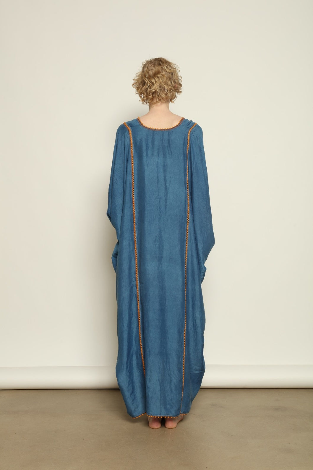 Model is wearing the Thea Blue Silk Dress by Supernaturae x HONS in deep indigo botanical-dyed silk chiffon, featuring a fluid ethereal silhouette and delicate hand-crochet edges. This sustainable slow luxury dress shows natural pigment variations that make each piece unique, crafted in small-batch production in Mexico using ancestral techniques. Part of the House of Woven Stories selection.