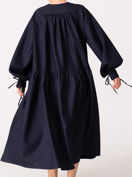 Model is wearing the Winter Calla Dress by Les Vacances d’Irina, a full-length navy merino wool dress with drop-waist silhouette, billowy sleeves, and bow cuffs, handmade in Bucharest and available at House of Nomad Stories.