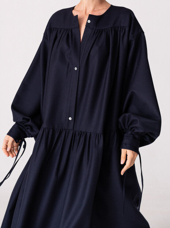 Model is wearing the Winter Calla Dress by Les Vacances d’Irina, a full-length navy merino wool dress with drop-waist silhouette, billowy sleeves, and bow cuffs, handmade in Bucharest and available at House of Nomad Stories.